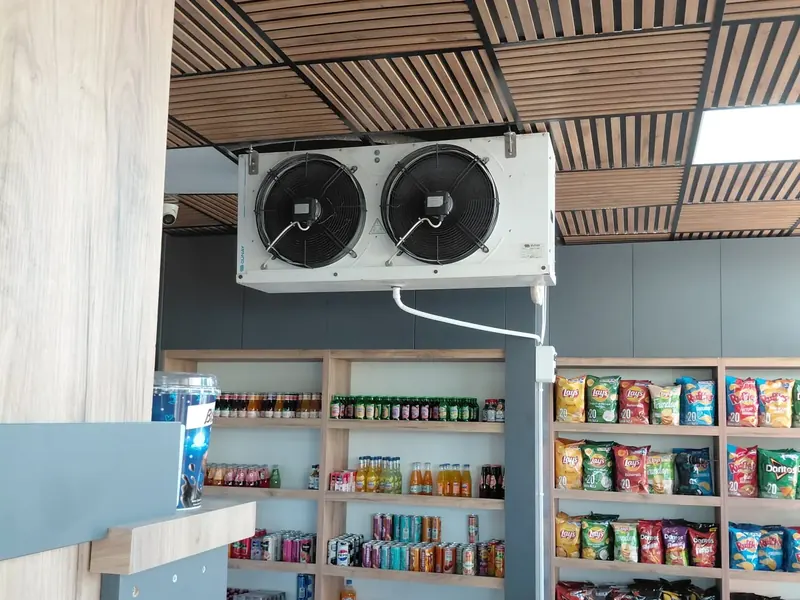 Two-fan cooling unit mounted on the ceiling above supermarket shelves